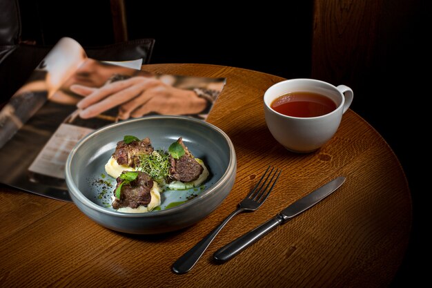 Steak grillé avec purée de légumes sur plaque sur table en bois.