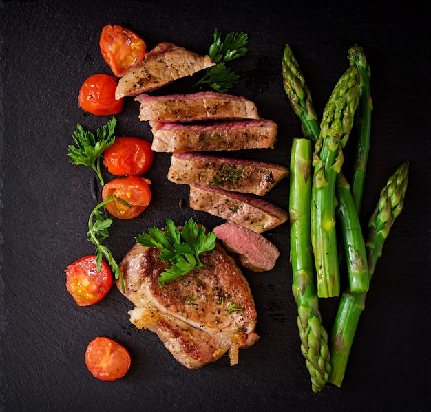 Steak juteux de boeuf mi-saignant aux épices et tomates, asperges. Vue de dessus