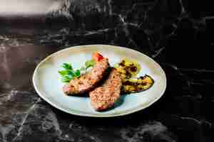 Photo gratuite steak de viande avec des aubergines grillées, du persil et des tomates dans une assiette blanche.