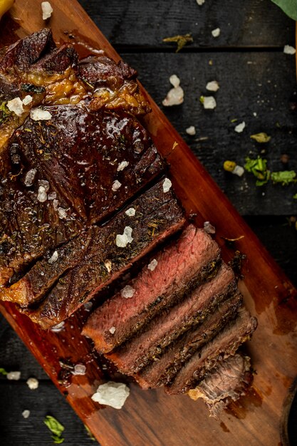 Steak de viande cuit cru tranché et sel ajouté, servi sur le tableau noir