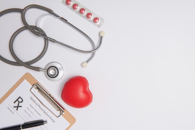 Stéthoscope avec coeur. Stéthoscope et coeur rouge sur table en bois. Concept d'assurance-vie hospitalière. Idée de la journée mondiale de la santé cardiaque. Concept de médecine ou de pharmacie. Formulaire médical vide prêt à être utilisé.