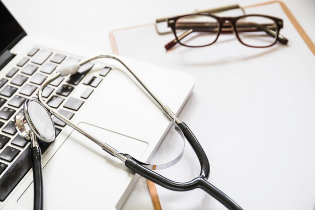 Stéthoscope sur ordinateur portable avec presse-papiers et lunettes