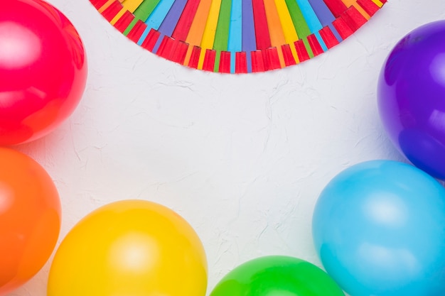 Stick arc-en-ciel et ballons colorés sur une surface blanche