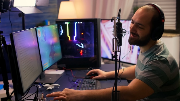 Streamer cyber exécutant un jeu vidéo de tir spatial sur un ordinateur puissant parlant avec des joueurs sur un chat ouvert pendant une compétition professionnelle