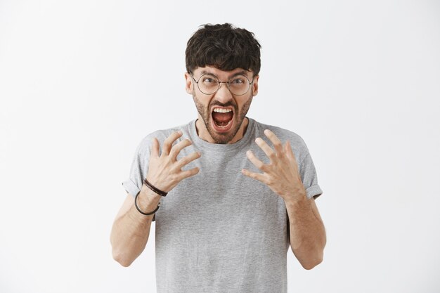 Stressé beau mec posant contre le mur blanc