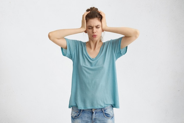 Photo gratuite stressé frustré jeune femme couvrant les oreilles avec les mains et fermant les yeux à cause du bruit