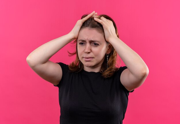 Stressé jeune femme décontractée avec les mains sur la tête sur un mur rose isolé