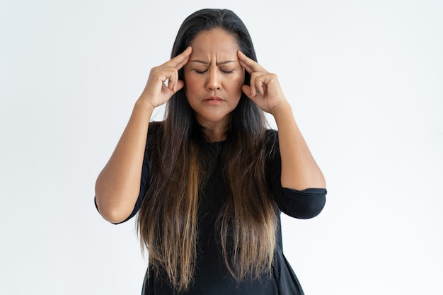 Stressée femme d&#39;âge moyen touchant les temples et réfléchissant