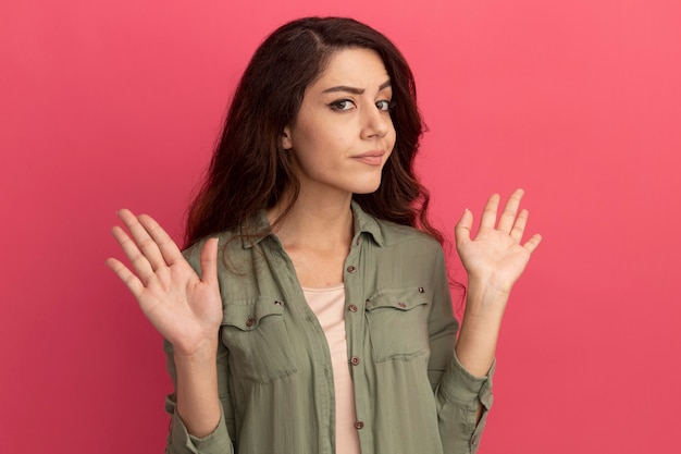 Stricte Jeune Belle Fille Portant Un T-shirt Vert Olive Répandant Les Mains Isolées Sur Le Mur Rose