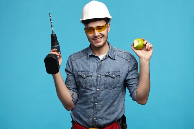 Studio photo de beau jeune homme à tout faire portant un casque et des lunettes posant