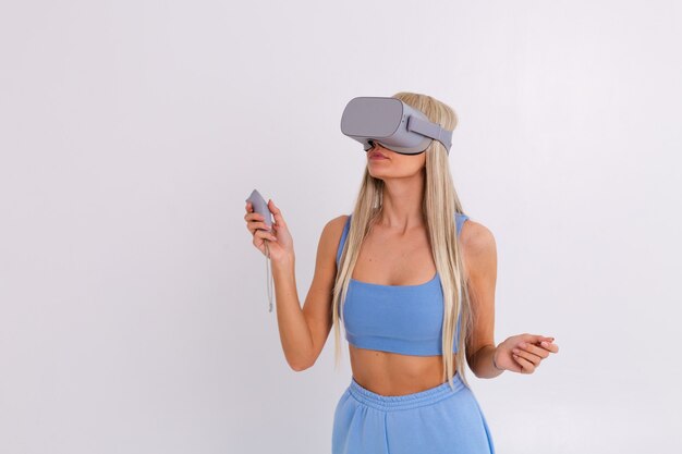 Studio photo d'une jeune femme séduisante dans un costume à la mode bleu chaud portant des lunettes de réalité virtuelle sur un blanc