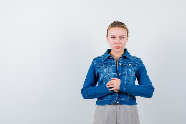 Studio shot of mad attractive blonde en denim bleu crochet mains et s'est fâché isolé sur fond blanc