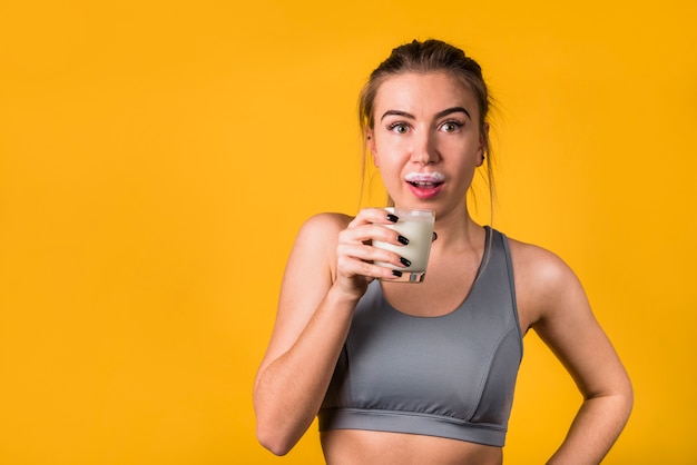 Stupéfié jolie jeune femme dans un vêtement de sport avec verre de lait