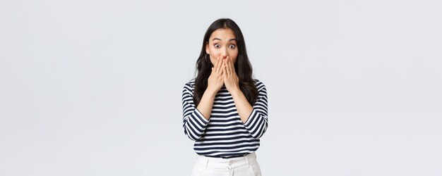 Style de vie émotions des gens et concept décontracté Une fille asiatique bavarde impressionnée aime les potins haletant couvrir la bouche et regarder sans voix debout étonné sur fond blanc