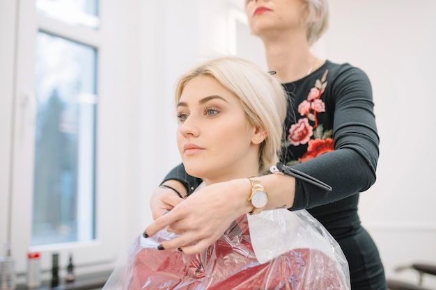 Styliste confiant prépare la jeune fille pour la coupe de cheveux