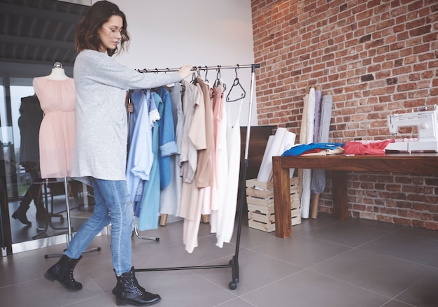 Photo gratuite styliste marchant avec tringle à vêtements