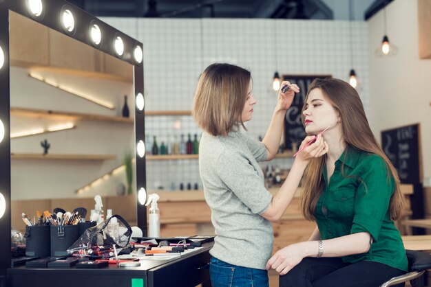 Styliste vue de côté avec eye-liner travaillant avec le modèle