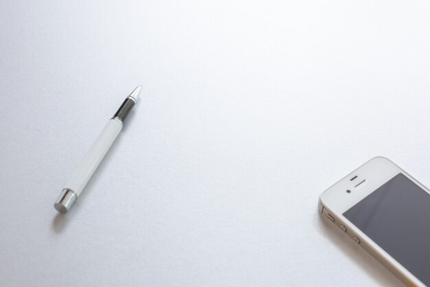 Un stylo blanc et un téléphone blanc sur fond blanc.