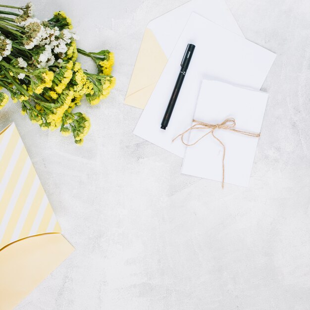 Stylo et cartes de vœux près du bouquet et du cadeau