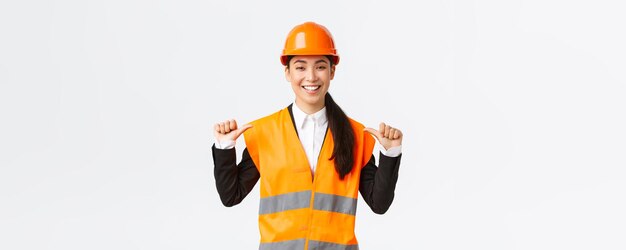 Succès fier souriant femme asiatique chef de la construction ingénieur dans un casque de sécurité pointant vers elle-même showoff Architecte recommande une assistance personnelle se vantant des réalisations