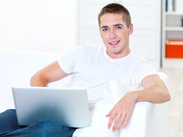 Succès jeune homme avec ordinateur portable à la maison