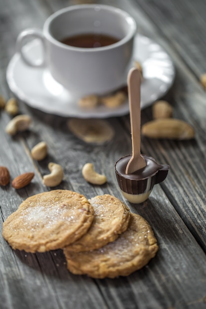 Sucette au chocolat en forme de petite tasse avec une tasse de thé et de noix sur bois