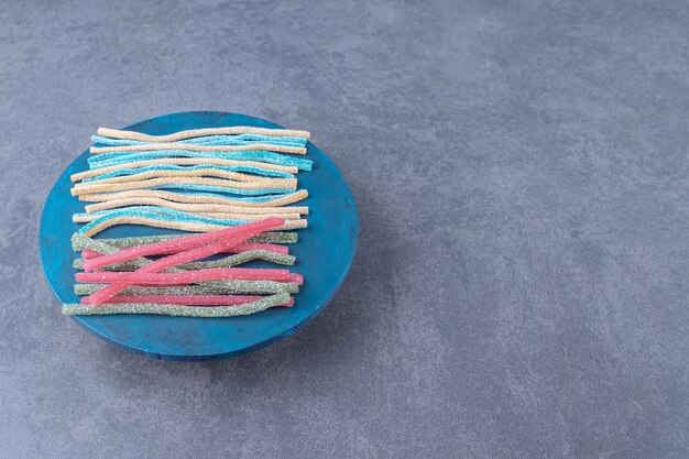 Sucre en poudre sur des bonbons à la réglisse sur une assiette sur une table en marbre