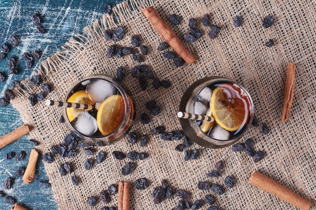 Sultane et fruits avec une tasse de boisson sur bleu.