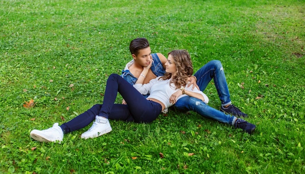Super couple décontracté allongé sur un champ d'herbe dans le parc.