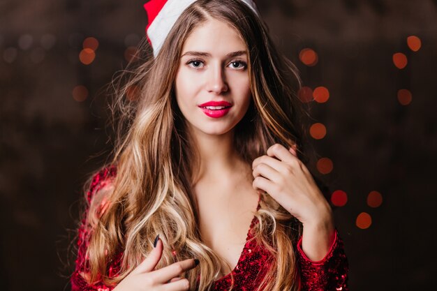 Superbe belle femme aux cheveux brun clair à la recherche d'appareil photo avec intetest au cours de la nouvelle année