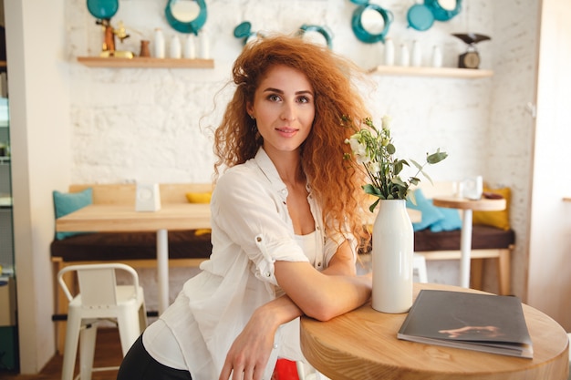 Superbe belle jeune femme rousse posant dans un café