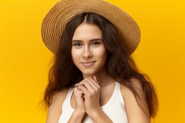 Superbe charmante jeune femme à la peau bronzée, maquillage naturel et cheveux lâches posant en studio