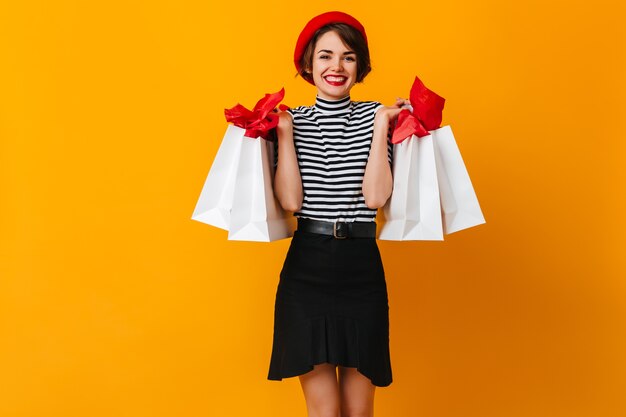 Superbe dame française tenant des sacs de magasin et souriant