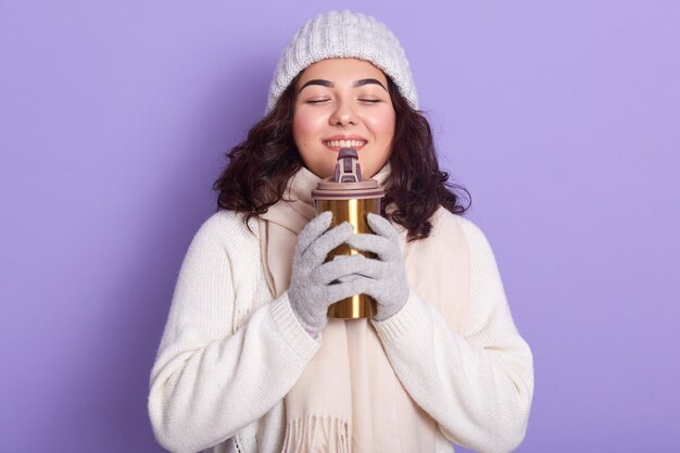 Superbe dame sentant le chocolat chaud de la tasse thermo