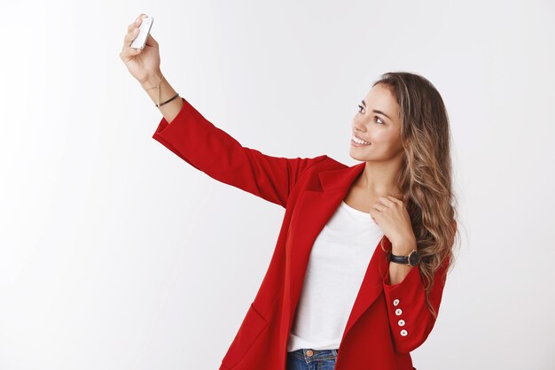 Superbe femme d'affaires moderne et réussie en veste rouge tendance prenant selfie