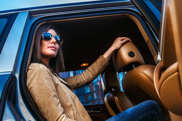 Superbe fille à lunettes de soleil sur les sièges arrière d'une voiture.