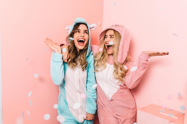 Photo gratuite superbe jeune femme en kigurumi bleu passant le week-end avec un ami adorables filles s'amusant à la soirée pyjama