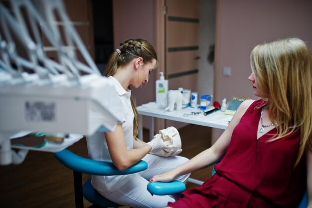 Superbe jeune orthodontiste posant avec un grand modèle de dent à côté de sa jolie patiente