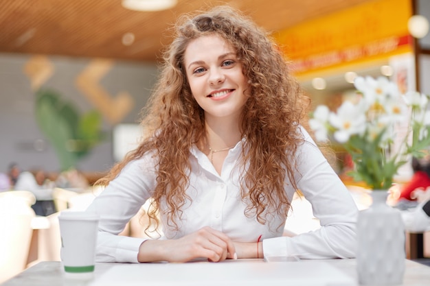 Superbe jolie jeune femme frisée en blouse blanche élégante