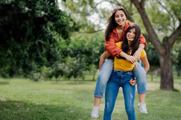 Superbes jeunes copines gaies d'Argentine s'amusant dans un parc en souriant