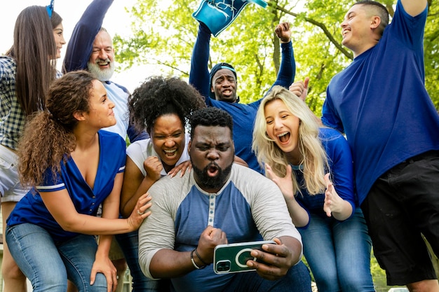 Les supporters regardent leur équipe gagner le match sur un téléphone portable