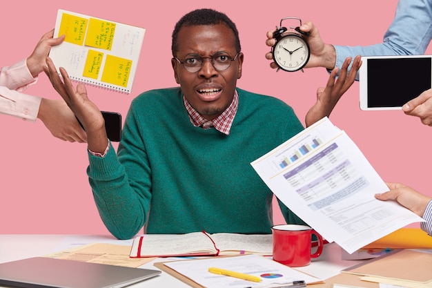 Photo gratuite surcharge de travail irrité, un homme afro-américain lève la main avec colère, en colère contre des collègues qui lui rappellent le travail