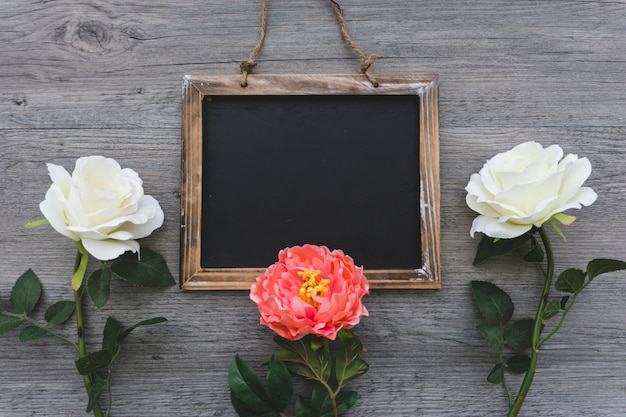 Surface en bois avec ardoise vierge et trois fleurs