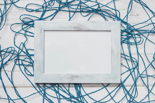 Surface en bois blanc avec corde bleue et cadre blanc