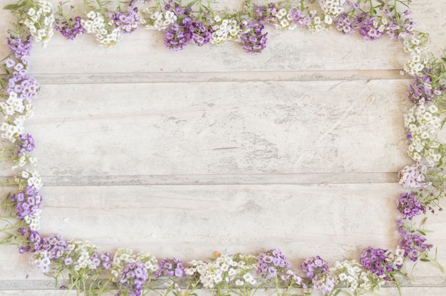 Photo gratuite surface en bois avec cadre en fleurs violettes et blanches