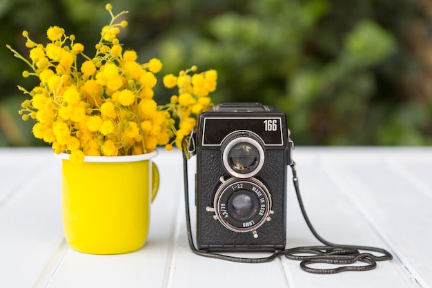 surface en bois avec des fleurs jaunes et appareil photo vintage