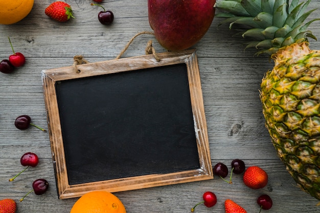 Surface en bois avec une variété de fruits et d&#39;ardoises vierges