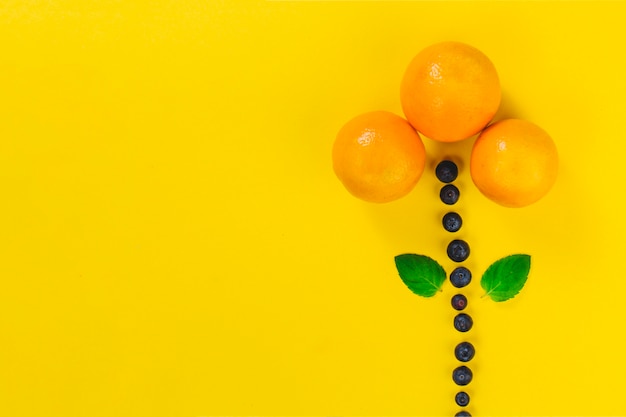Surface jaune avec fleur faite de fruits d&#39;été