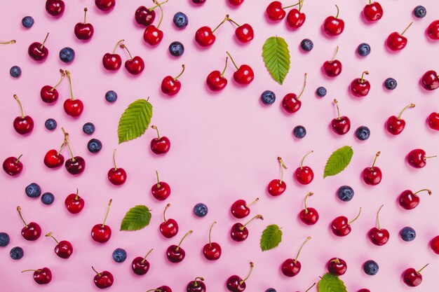 Surface rose avec des myrtilles et des cerises savoureuses