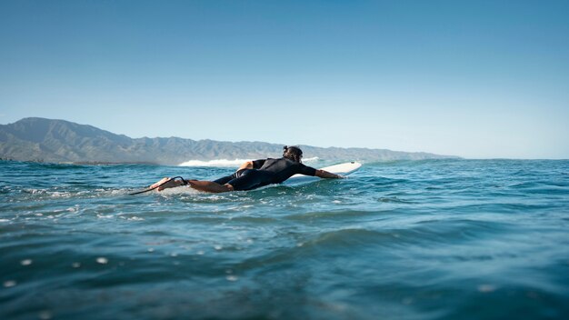 Surfer nage dans l'eau long shot